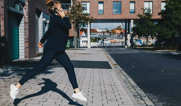 Voys-Kolleg:in springt vor Freude in die Luft – mit dem Telefon am Ohr und der VoIP-App in Verwendung.