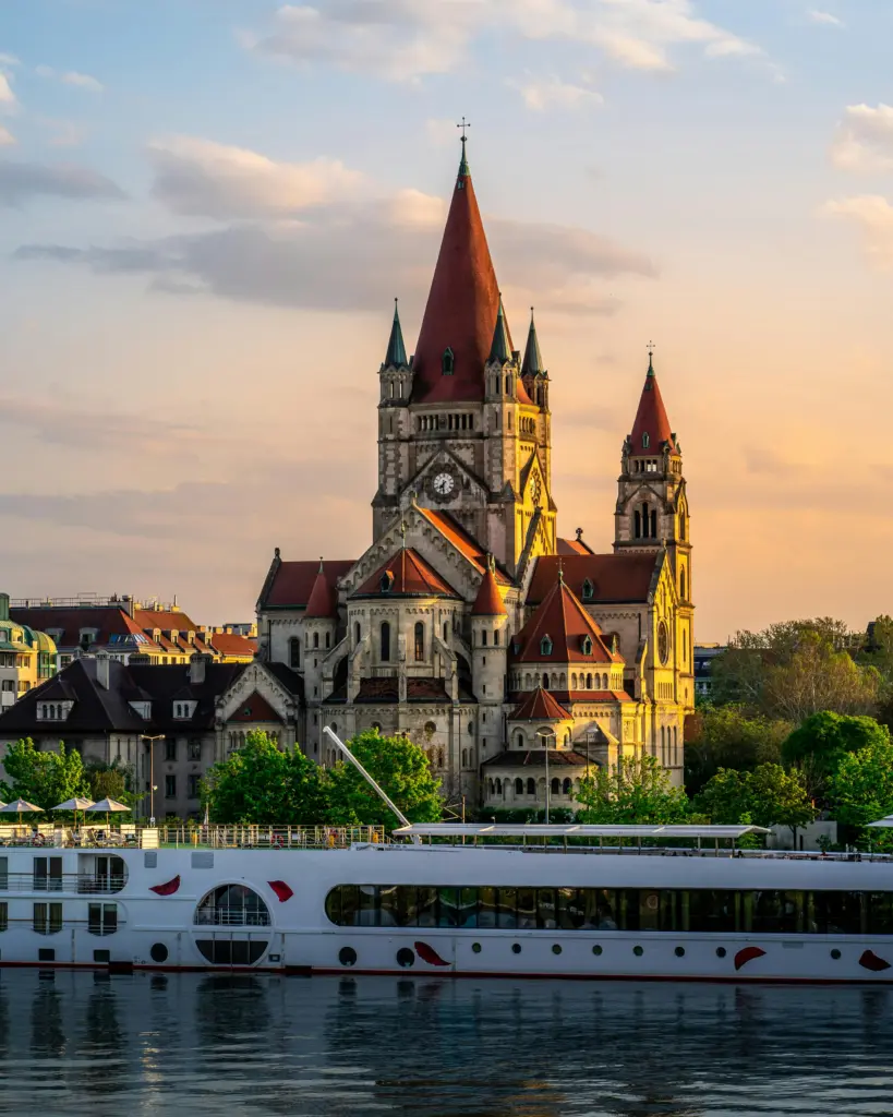 Landschaftsaufnahme einer österreichischen Stadt von gegenüber einem See, mit einer vorbeifahrenden Fähre.