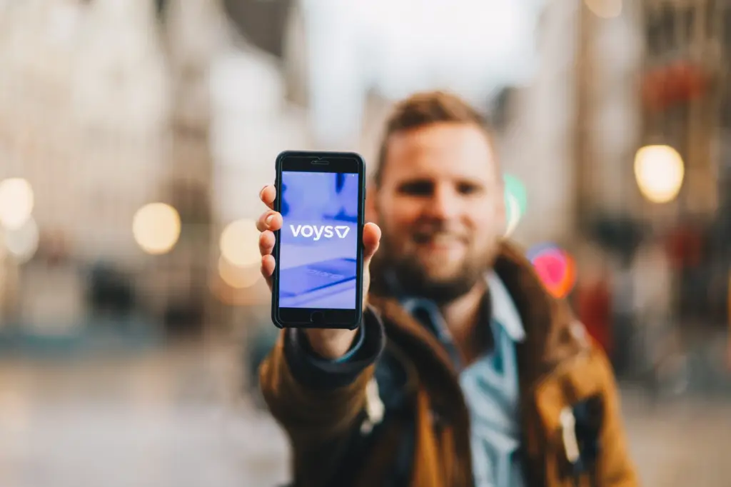 ’n Voys-kollega hou ’n slimfoon vas waarop die Voys-toep hetoon word.