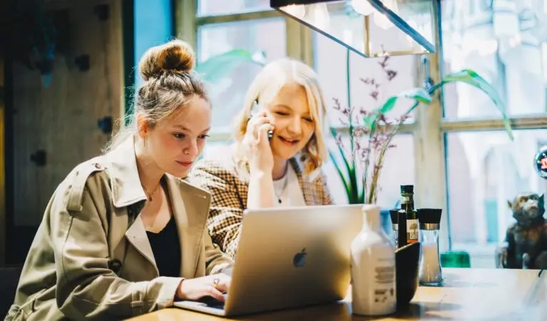 Zwei Frauen sitzen an ihrem Schreibtisch und nutzen die VoIP-Telefonie von Voys für geschäftliche Zwecke.