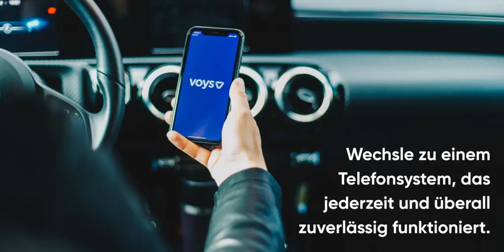 Person hält ein Smartphone mit geöffneter Voys App – eine professionelle Telefonnummer mit der Vorwahl 0211 ist sichtbar.