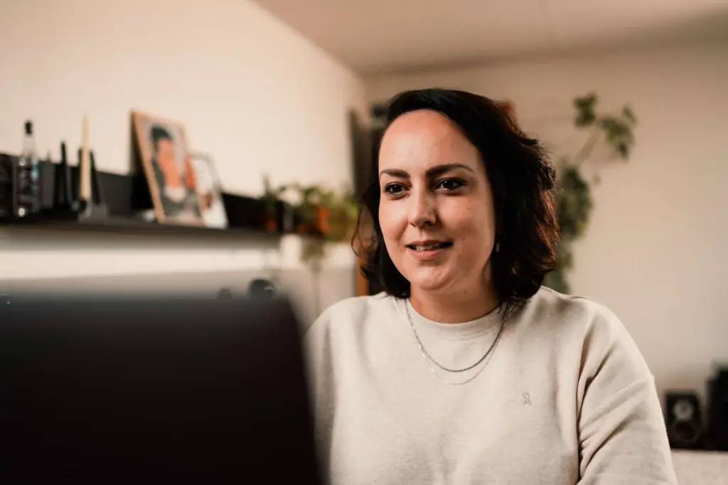 Collega Maya zit achter haar laptop te werken in een thuissetting.