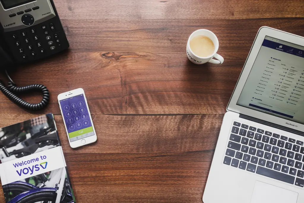 Voys VoIP tech on the desk, Cellphone with Voys app and Laptop with Freedom