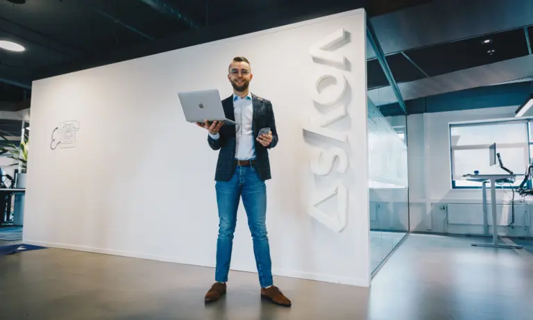 Colleague standing at Voys headquarters with laptop in hand